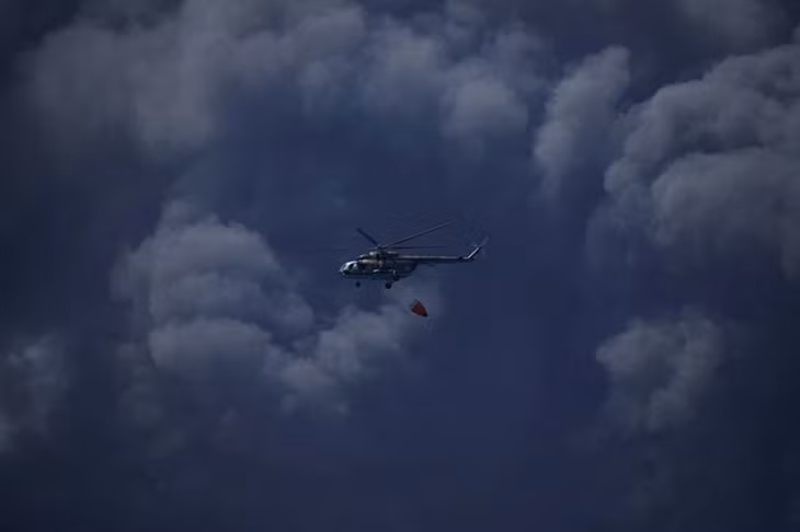 Một chiếc trực thăng chuẩn bị thả nước xuống kho dầu. (Ảnh: Reuters)