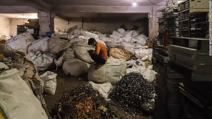 Người đàn ông ngồi trên đống rác thải điện tử tại một cửa hàng ở New Delhi, Ấn Độ tháng 7/2020. (Ảnh: Shutterstock)