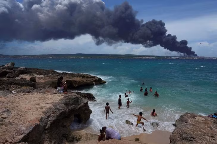 Một nhóm người đang tắm biển gần khu vực diễn ra vụ cháy. (Ảnh: Reuters)