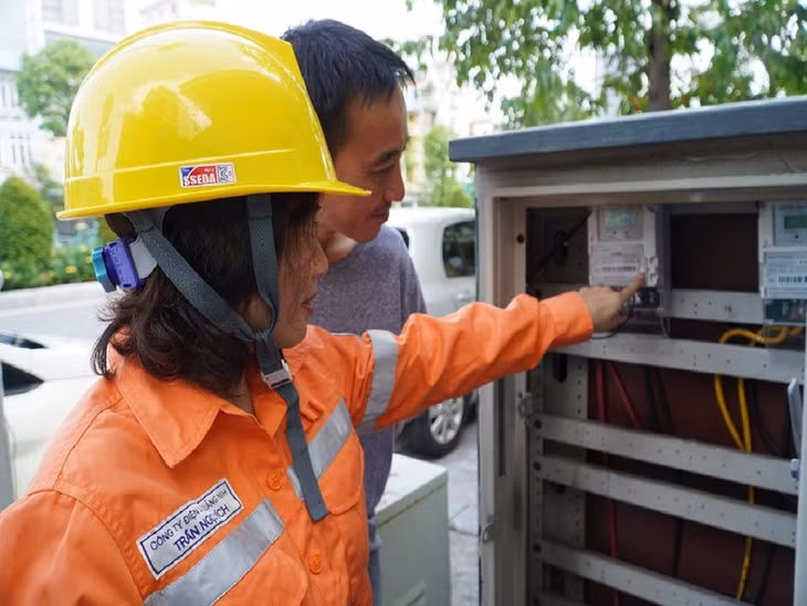 Công nhân Điện lực TP Hạ Long hướng dẫn khách hàng kiểm tra chỉ số công tơ tiêu thụ điện.