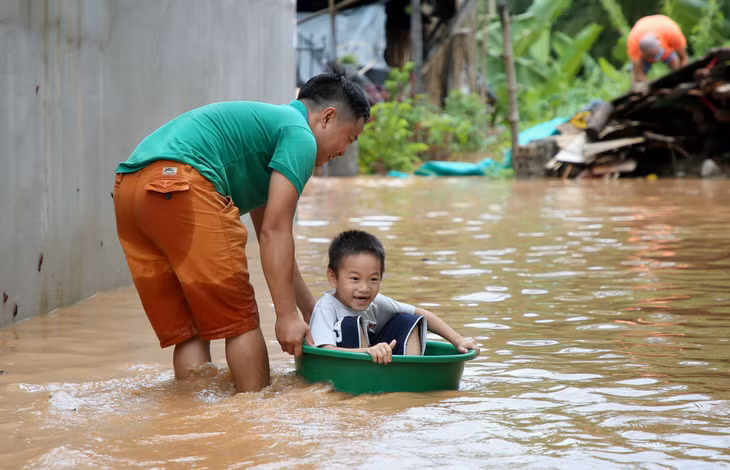 Nhiều bạn nhỏ được người lớn đưa đi sơ tán khỏi vùng ngập lụt bằng "xuồng" chậu.