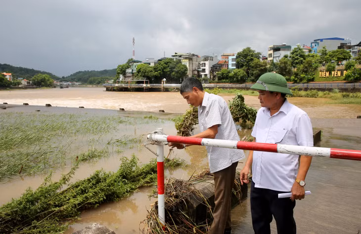 Cán bộ thị trấn Tiên Yên kiểm tra khóa barie ngăn người và phương tiện qua lại ngầm tràn sông Tiên Yên khi nước lũ lên cao.