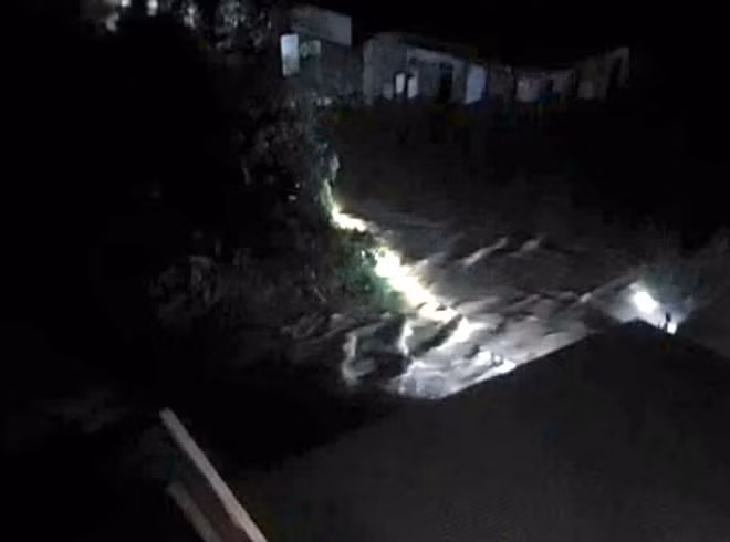 Vị trí hai người bị nước lũ cuốn trôi may mắn được cứu sống. Ảnh cắt từ clip