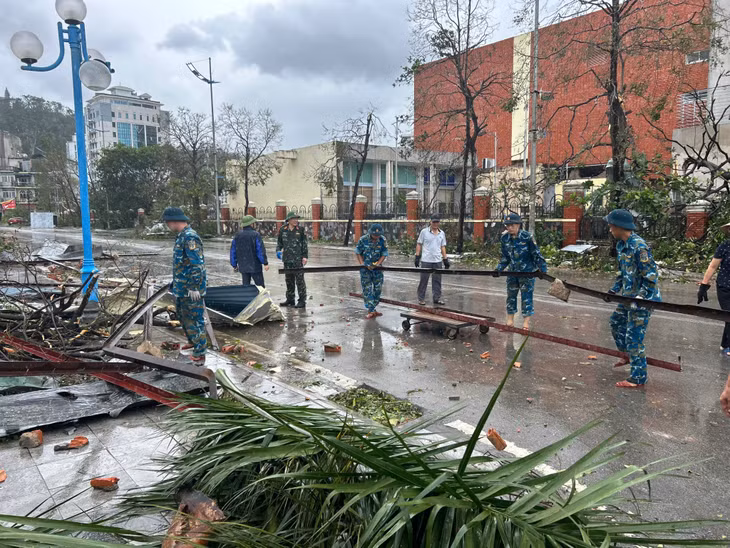 Cán bộ chiến sĩ Trung đoàn 213 tham gia hỗ trợ các cơ quan, người dân thu dọn vệ sinh, cây gãy đổ sau cơn bão số 3. Ảnh: Thu Chung - Trúc Linh