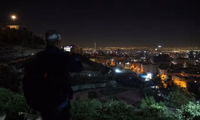 Người đàn ông quay cảnh thủ đô Tehran khi những tiếng nổ lớn vang lên bên trong thành phố rạng sáng 26/10. Ảnh: Reuters