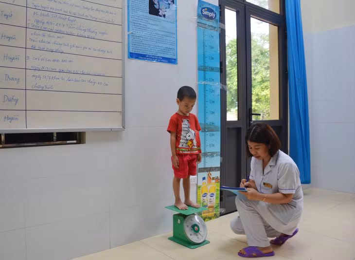 Nhân viên y tế của Trạm Y tế xã Quảng La (TP Hạ Long) thực hiện cân, đo kiểm tra sức khỏe cho trẻ em trên địa bàn.