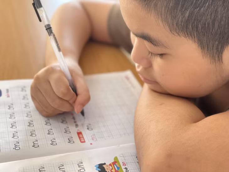 Em Phạm Đức Minh nắn nót tập tô chữ.