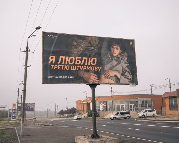 Áp phích có hình mẫu nữ nằm trên đùi người lính Ukraine. Ảnh: WP