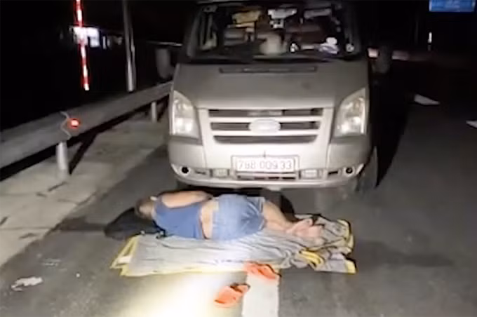 Tài xế ngủ trước đầu xe đang dừng trên cao tốc Vĩnh Hảo - Phan Thiết. Ảnh: Công an cung cấp