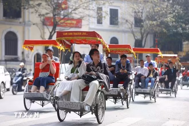 Du khách quốc tế trải nghiệm du lịch bằng xích lô quanh hồ Hoàn Kiếm, Hà Nội. (Ảnh: Minh Quyết/TTXVN)