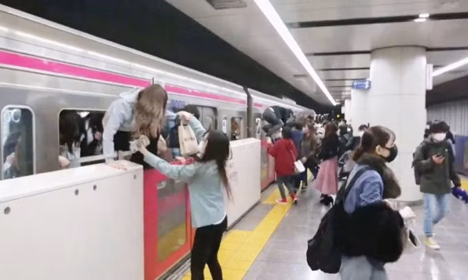 Hành khách chui qua cửa sổ để tháo chạy kẻ tấn công khi đoàn tàu vào ga Kokuryo ở Tokyo hôm nay. Ảnh: Kyodo.