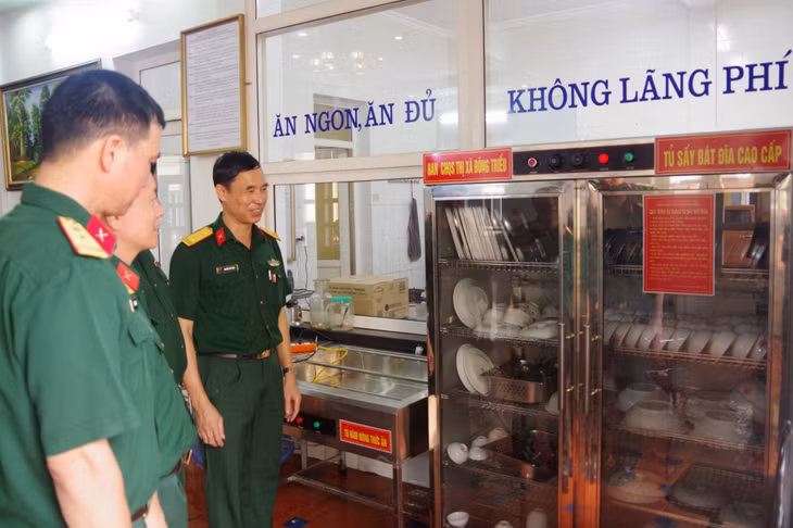 Đại tá Nguyễn Hữu Cảnh (ngoài cùng, bên phải), chủ nhiệm chính trị Bộ CHQS tỉnh cùng đoàn công tác tham quan sáng kiến (tủ giữ ấm thức ăn, tủ sấy bát đĩa) tại nhà ăn Ban CHQS TX Đông Triều.