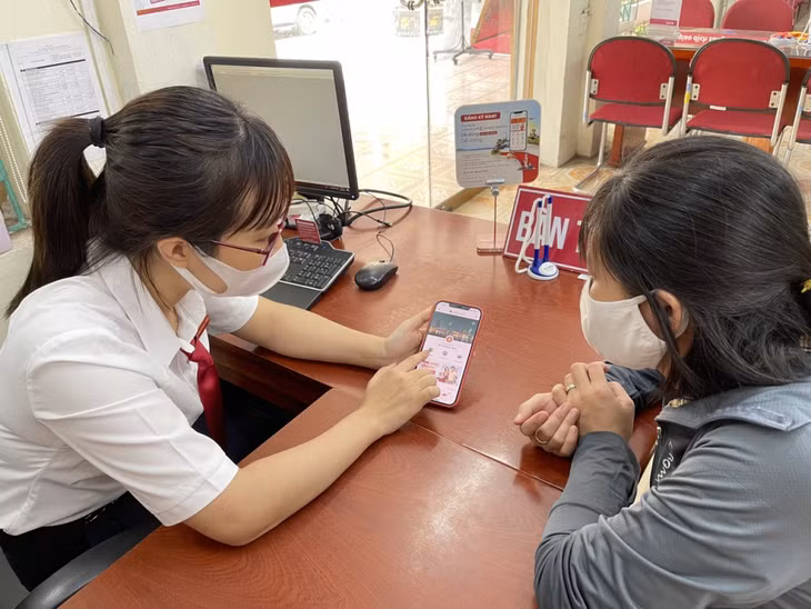 Cán bộ Agribank chi nhánh Tây Quảng Ninh hướng dẫn người dân sử dụng dịch vụ E-Mobile banking.