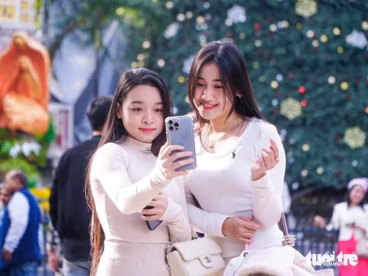 Các cô gái chụp ảnh để lưu lại những kỷ niệm đẹp trong những ngày Giáng sinh se lạnh ở Hà Nội - Ảnh: PHẠM TUẤN