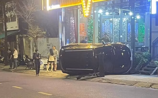 Chiếc xe ô tô đâm vào nhóm người đứng trên vỉa hè rồi lật nghiêng. Ảnh: H.Nguyên