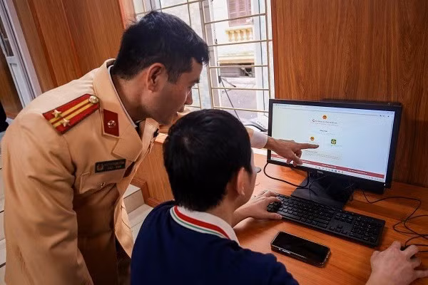 Cảnh sát giao thông hướng dẫn người dân làm thủ tục cấp đổi giấy phép lái xe. Ảnh: Xuyên Đông