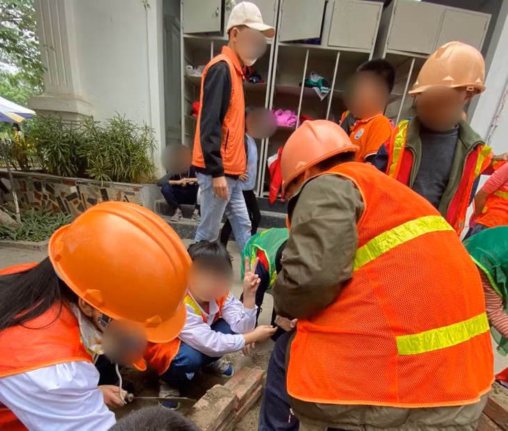 Trẻ em đang được người lớn hướng dẫn để trải nghiệm một ngày làm công nhân xây dựng. Ảnh: Đức Vân