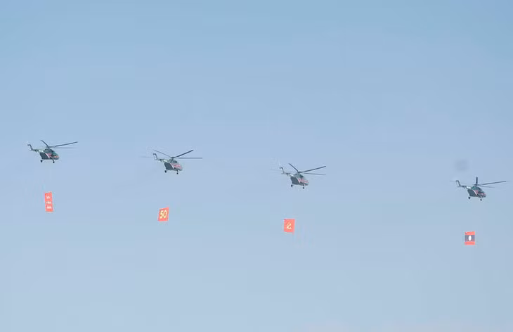 Biên đội máy bay trực thăng mang cờ bay trên bầu trời khu vực tổ chức lễ kỷ niệm. (Ảnh: Thống Nhất/TTXVN)