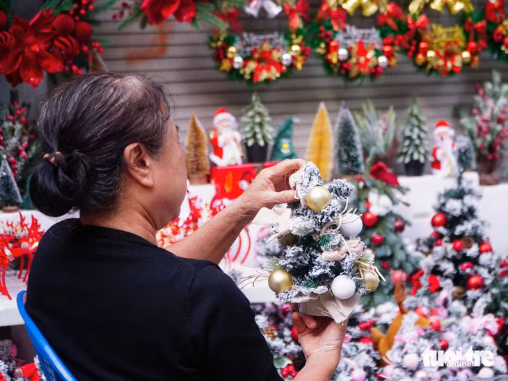Một người phụ nữ đang trang trí cây thông Noel mini trước khi bày biện ra bán cho khách - Ảnh: PHẠM TUẤN