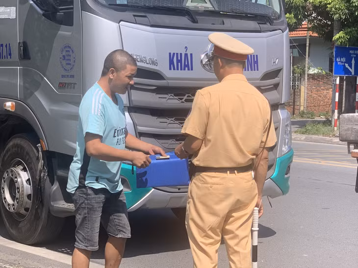 Cán bộ Đội CSGT đường bộ số 1 kiểm tra hành chính chủ phương tiện vận tải hàng hoá trên QL18A đoạn đi qua địa bàn TP Đông Triều.