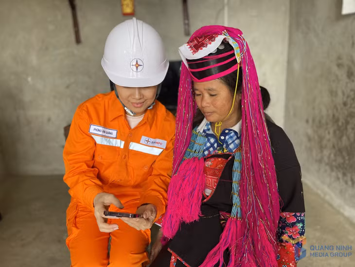 Công nhân Đội Quản lý điện lực khu vực Hải Hà hướng dẫn người dân xã Đường Hoa thanh toán tiền điện trực tuyến.