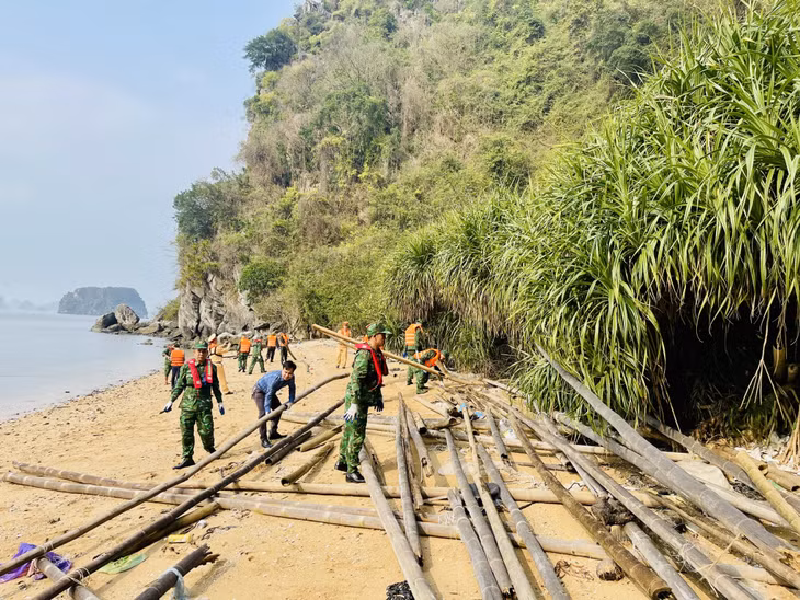 Các lực lượng chức năng thu gom bè mảng trôi dạt vào các khe, chân núi đá ở khu vực hòn Cặp Liền.