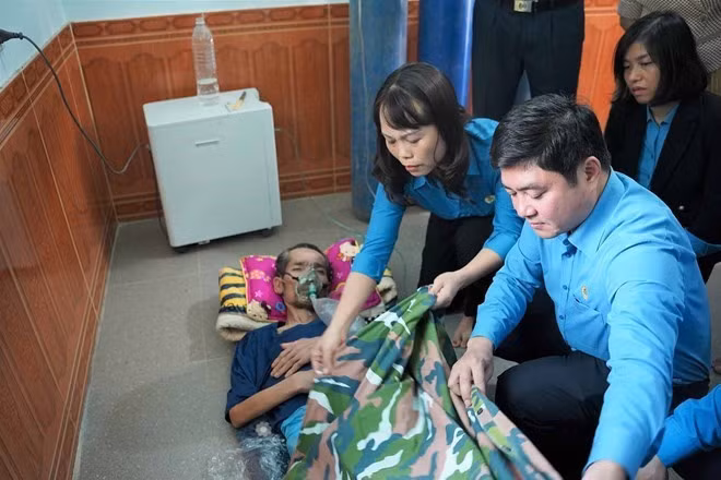 Đoàn công tác Tổng LĐLĐ Việt Nam và Công đoàn Khu kinh tế Đông Nam Nghệ An thăm công nhân Hoàng Văn Sơn khi đang điều trị bệnh bụi phổi. Ảnh: Quang Đại