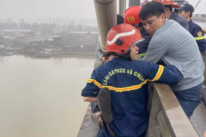 Lực lượng chức năng lao vào ôm giữ, kéo nam thanh niên lên cầu. Ảnh: Xuân Tân
