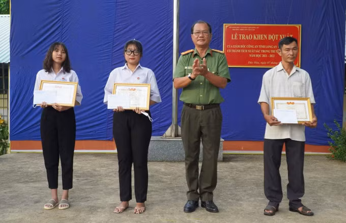 Đại diện Công an tỉnh Long an trao giấy khen cho hai học sinh cùng người dân. Ảnh: Thảo Nguyên