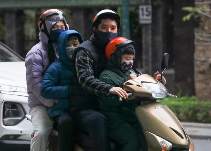 Một gia đình với trang phục ấm di chuyển trên phố Trần Hưng Đạo. (Ảnh: Hoàng Hiếu/TTXVN)