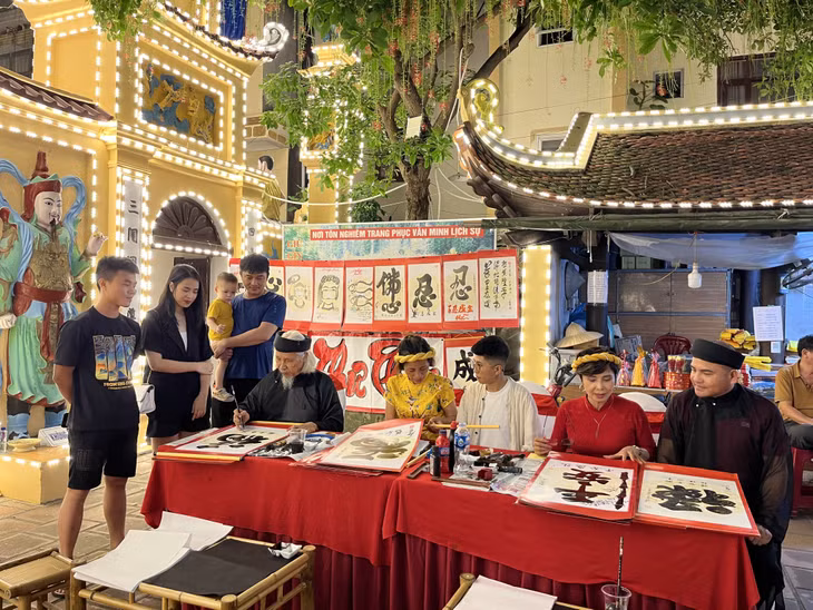 Nhà thư pháp Lê Thiên Lý (thứ 5, phải sang) và các học trò cho chữ ở không gian Phố đi bộ Bài Thơ (TP Hạ Long).