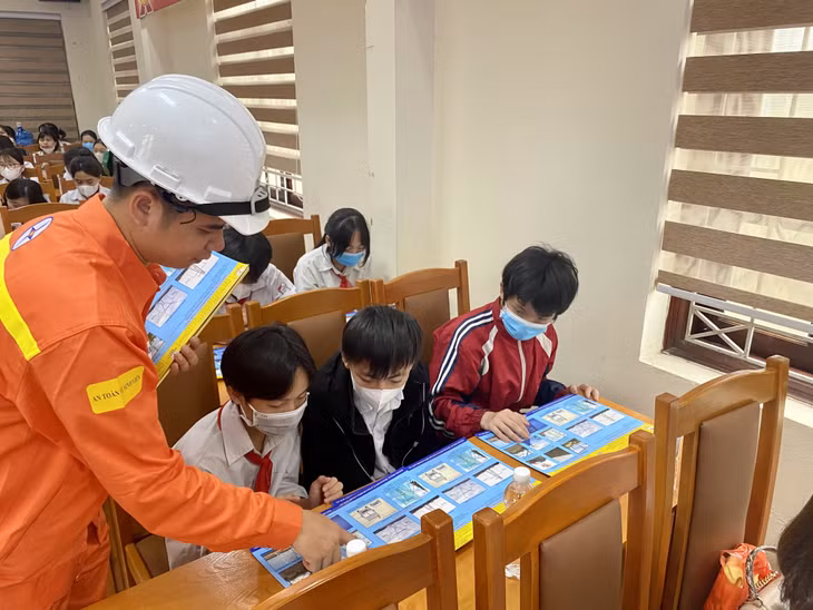 Công nhân quản lý vận hành của Truyền tải điện Đông Bắc 1 phát tờ rơi cho các học sinh Trường TH&amp;THCS Dương Huy về một số hành vi bị nghiêm cấm, gây sự cố lưới điện.
