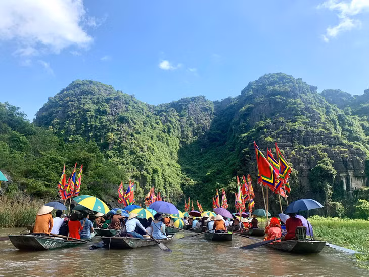 Thuyền chở những chiếc cờ ngũ sắc rực rỡ trên dòng sông Ngô Đồng - Ảnh: Sở DL Ninh Bình cung cấp