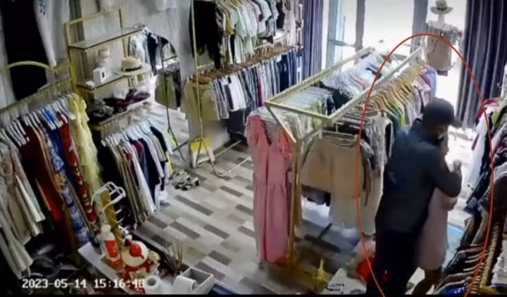 Ảnh cắt từ video ghi lại cảnh tên cướp dùng dao khống chế chủ cửa hàng quần áo.