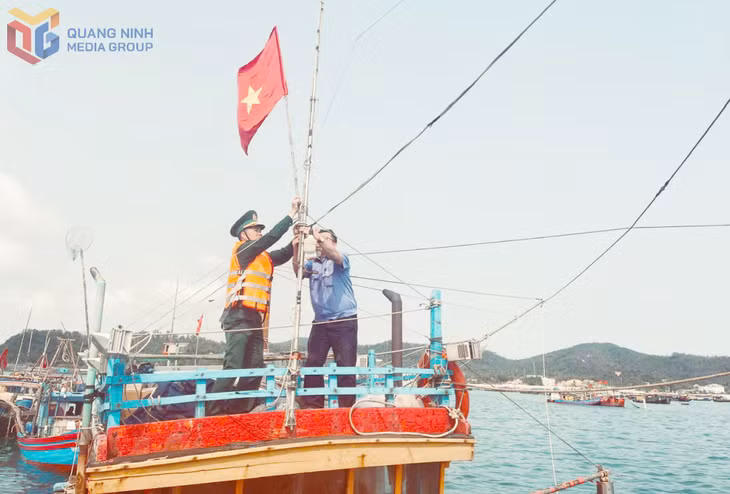 Cán bộ Đồn Biên phòng Thanh Lân giúp ngư dân treo cờ Tổ quốc.