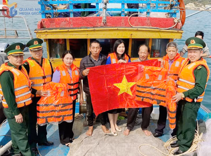 Cán bộ Đồn Biên phòng Thanh Lân phối hợp tặng cờ Tổ quốc cho các tàu cá trên vùng biển Cô Tô.