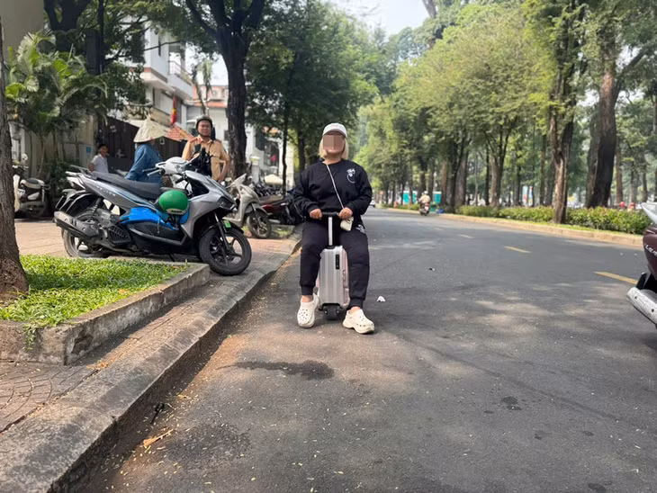 Bà T.T.N.T. "cưỡi" vali di chuyển ở đường Lê Duẩn, quận 1. Ảnh: Phòng CSGT