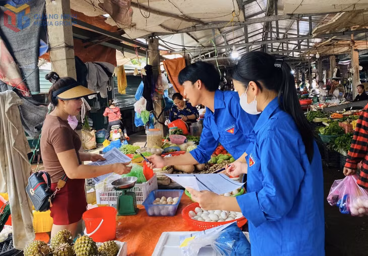 ĐVTN xã Đông Hải (huyện Tiên Yên) hướng dẫn tiểu thương tại chợ Đông Hải áp dụng việc thanh toán không dùng tiền mặt. Ảnh: Ngọc Trâm