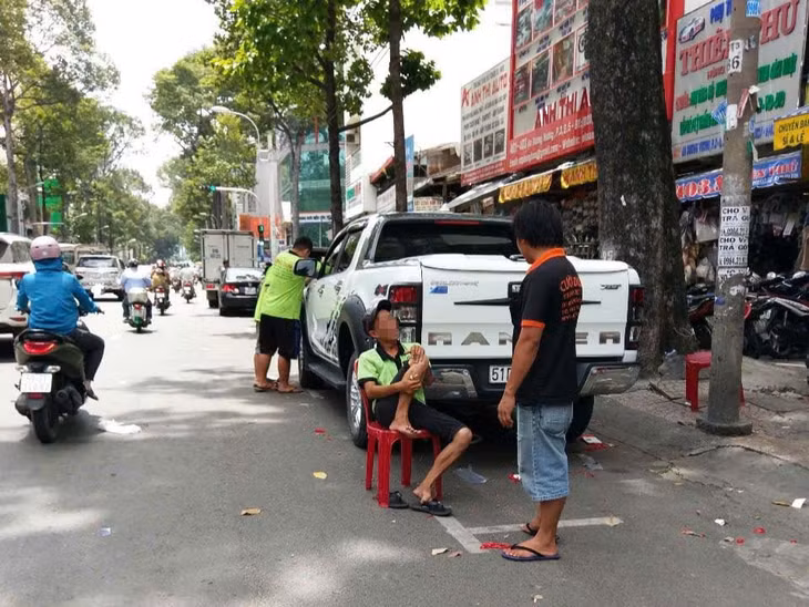 Ngồi ghế giữ chỗ đỗ ôtô thu phí trên đường An Dương Vương (Quận 5). Ảnh: Minh Quân