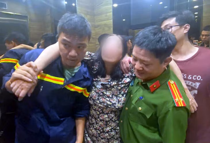 Các chiến sĩ công an đưa người phụ nữ xuống nơi an toàn. Ảnh: CACC