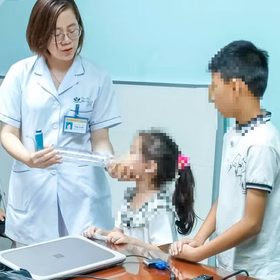 Điều dưỡng Trịnh Thị Hậu, Khoa Miễn dịch – Dị ứng – Khớp, Bệnh viện Nhi Trung ương hướng dẫn cha mẹ và các bé cách xịt thuốc dự phòng hen tại nhà. Ảnh BVNTW