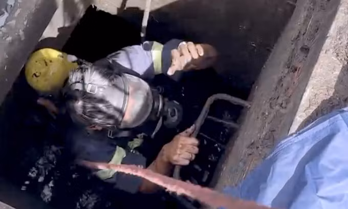 Cảnh sát mang mặt nạ chống độc, bình oxy xuống cống cứu người. Ảnh: Minh Điệp