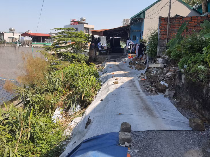 Để lấy lối đi lại, các hộ gia đình trong xóm đã đắp đất, phủ bạt mặt đường.