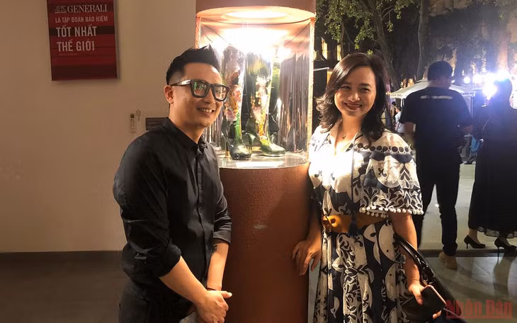 Anh Vũ Khánh Tùng (trái) bên tác phẩm của cha mình để lại.