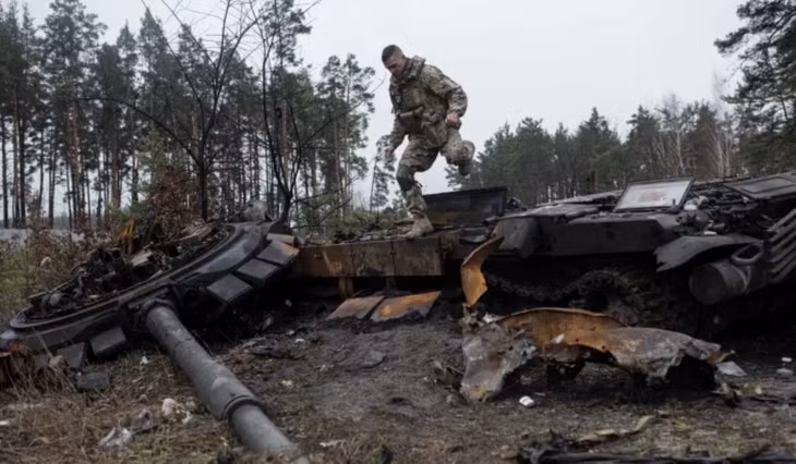 Binh sĩ Ukraine vượt qua một xác xe tăng ở Dmytrivka, ngoại ô Kiev ngày 2/4/2022. Ảnh: Getty Images