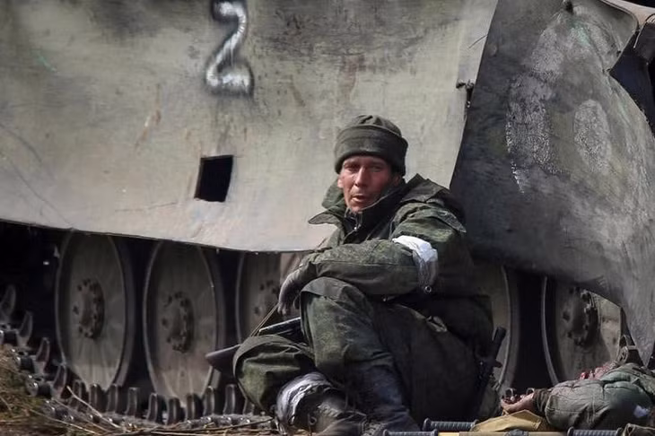 Một binh sĩ Nga ngồi cạnh xác đồng đội thiệt mạng trong giao tranh ở thành phố Mariupol, Ukraine. Ảnh: Reuters