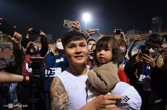 Quang Hải bế cháu gái, chào CĐV trong trận đấu cuối cùng của anh cho CLB Hà Nội trên sân Hàng Đẫy ngày 4/4. Ảnh: Lâm Thoả