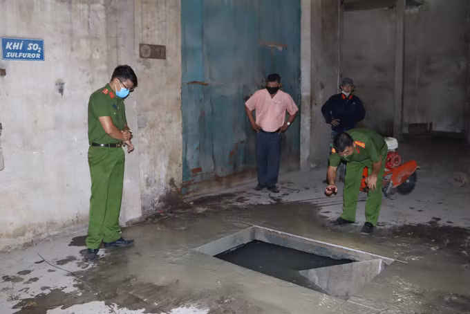 Cảnh sát kiểm tra hầm chứa chất thải chưa qua xử lý trong khuôn viên xí nghiệp đèn ống. Ảnh: Thái Hà