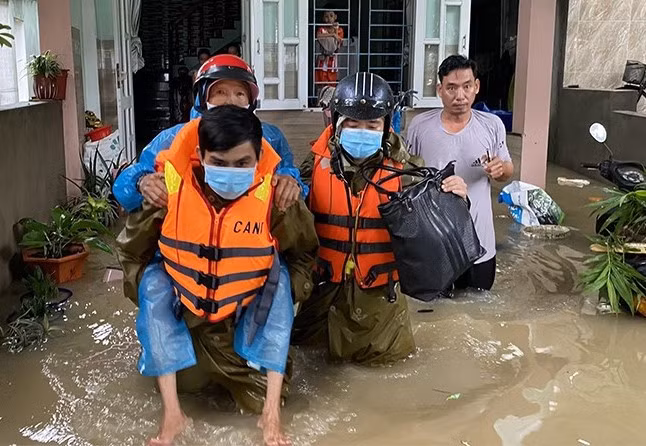 Công an huyện Tuy Phước vào thôn Hưng Nghĩa, xã Phước Nghĩa bị cô lập do lũ hỗ trợ đưa một người già bị bệnh đi cấp cứu.