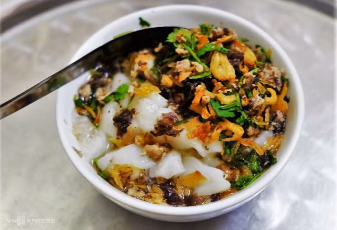 Bánh đúc nóngĐây thực chất là một cách biến tấu khác của món bánh đúc truyền thống, thay vì để nguội cắt miếng chấm tương thì bánh đúc được ăn trong lúc vẫn còn đang đun nóng và dẻo quánh. Bánh đúc nóng sẽ ăn kèm nước chấm chua ngọt, thịt xay xào mộc nhĩ, rau mùi tươi xắt nhỏ, hành khô phi vàng và rắc thêm tiêu, ớt bột. Khoảng 15.000 - 20.000 đồng một bát vừa vặn để lót dạ xế chiều. Một số địa chỉ bán bánh đúc nóng đông khách hiện nay nằm ở phố Lê Ngọc Hân, khu tập thể Trung Tự, phố Nguyễn Hiền... Ảnh: Khánh Trần